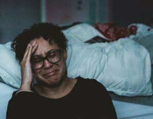 Woman on side of bed crying from depression