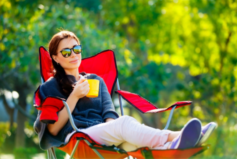 a woman sitting in chair with sunglasses and a cup of coffee