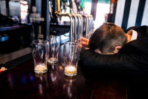 A man passed out at a bar because of alcohol addiction.