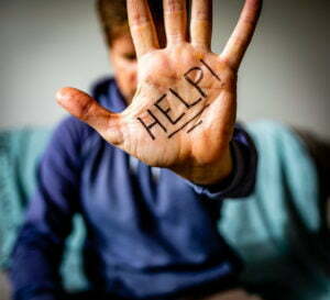 A man with the word "help" written on his hand